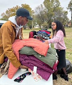 Jonathan Birl, left, and Ember Martin sort coats during the inaugural Landmark Pentecostal Church coat giveaway Saturday, Nov. 19, 2022, in a vacant lot near Texarkana Public Library in Texarkana, Texas. The drive was organized by Landmark at the urging of pastor Jason Calhoun. The congregation, which meets at 1601 Mall Drive, collected the coats through donation boxes placed in the church's lobby and Event Center and the Elite Academy. About 100 coats were distributed during the giveaway, which was from 11 a.m. to 2 p.m. Remaining coats were given to Mission Texarkana. Golden Corral donated a soup meal for the event. (Submitted photo)