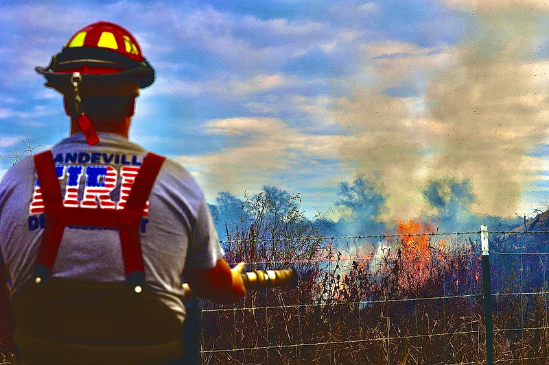 A Mandeville Volunteer Firefighter works a fire near County Roads 296 and 378 on Monday afternoon, Nov. 21, 2022, in Miller County, Ark. A controlled burn got out of control due to high winds. (Photo by JD)