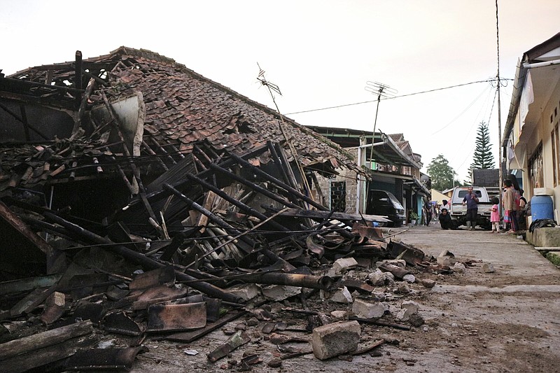 Residents examine a house flattened by earthquake in Cianjur, West Java, Indonesia, Monday, Nov. 21, 2022. The strong, shallow earthquake toppled buildings and collapsed walls on Indonesia's densely populated main island of Java on Monday, killing a number of people and injuring hundreds as people rushed into the streets, some covered in blood and white debris. (AP Photo/Rangga Firmansyah)