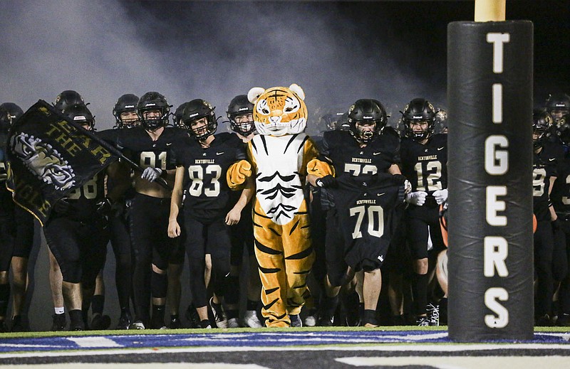 Bentonville players run out onto the field carrying James Maunu's No. 70 jersey on Thursday, November 3, 2022 during a football game at Tiger Stadium. Maunu died on June 19 from complications related to diabetes. He was a member of the Bentonville Tiger football team. 
(NWA Democrat-Gazette/Charlie Kaijo)