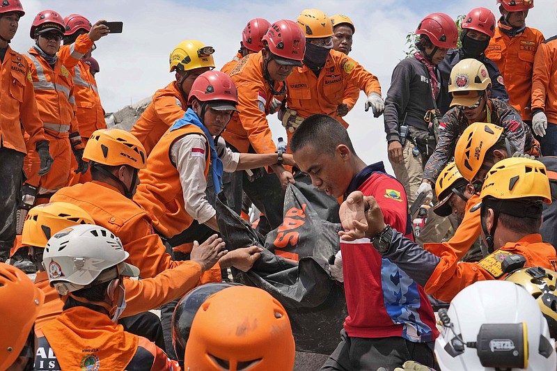 Rescuers recover the body of an earthquake victim from under the rubble of a collapsed building in Cianjur, West Java, Indonesia,Tuesday, Nov. 22, 2022. Rescuers on Tuesday struggled to find more bodies from the rubble of homes and buildings toppled by an earthquake that killed a number of people and injured hundreds on Indonesia's main island of Java. (AP Photo/Tatan Syuflana)