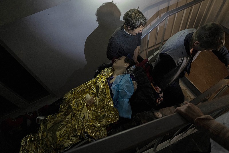 Staff carry 13-year-old Arthur Voblikova on a stretcher up the stairs to the operating room inside a hospital in Kherson, southern Ukraine, Tuesday, Nov. 22, 2022. Arthur Voblikova was injured after a Russian strike, and doctors had to amputate his left arm. As attacks increase in the recently liberated city of Kherson, doctors are struggling to cope amid little water, electricity and a lack of equipment. (AP Photo/Bernat Armangue)