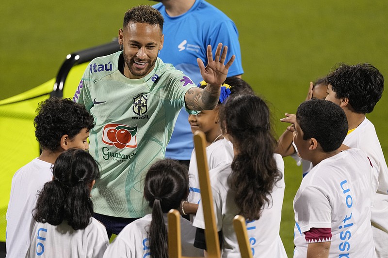 Neymar saluda a niños de un proyecto de la FIFA en un entrenamiento en el estadio Grand Hamad en Doha, Qatar, el 20 de noviembre de 2022. (AP Foto/Andre Penner)