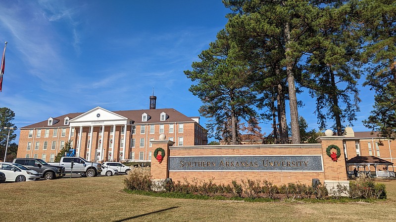 Wreaths sit on the sign outside of Overstreet while staff decorate the tree and gazebo in the background. (Joshua Turner / Banner News)