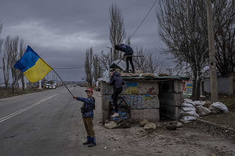 Ukrainian children play at an abandoned checkpoint in Kherson, southern Ukraine, Wednesday, Nov. 23, 2022. A new onslaught of Russian strikes on Ukrainian infrastructure on Wednesday caused power outages across the country — and in neighboring Moldova — further hobbling Ukraine's battered electricity network and compounding civilians' misery as winter advances. (AP Photo/Bernat Armangue)