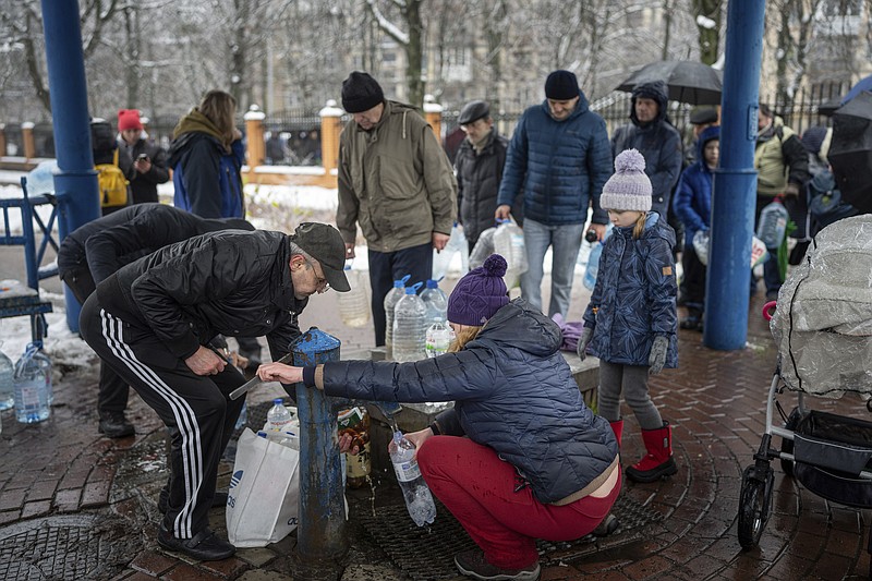 People collect water, in Kyiv, Ukraine, Thursday, Nov. 24, 2022. Residents of Ukraine's bombed but undaunted capital clutched empty bottles in search of water and crowded into caf&#xe9;s for power and warmth Thursday, switching defiantly into survival mode after new Russian missile strikes a day earlier plunged the city and much of the country into the dark.  (AP Photo/Evgeniy Maloletka)