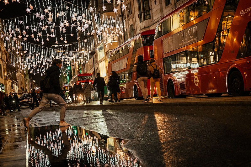 A pedestrian jumps over a puddle under illuminated Christmas lights along Oxford Street in London on Nov. 23. MUST CREDIT: Bloomberg photo by Jose Sarmento Matos.