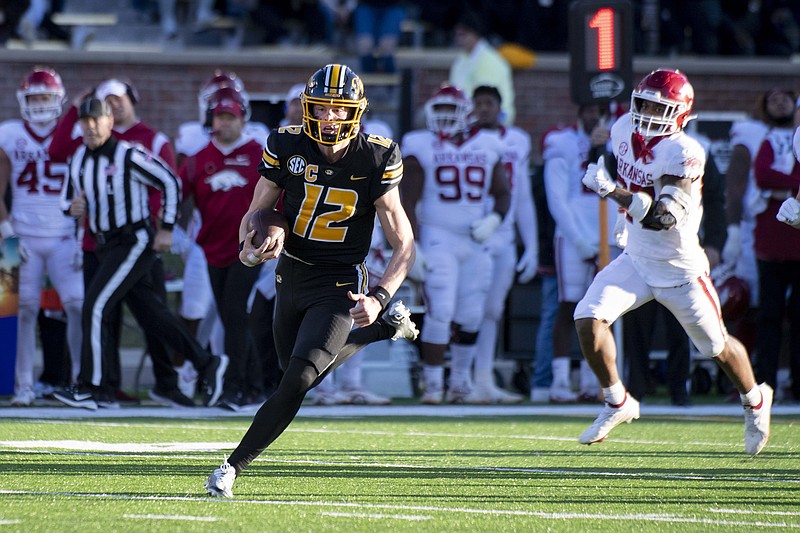 Missouri quarterback Brady Cook, left, runs past Arkansas linebacker Chris Paul Jr., right, during the second quarter Friday in Columbia, Mo. - Photo by L.G. Patterson of The Associated Press