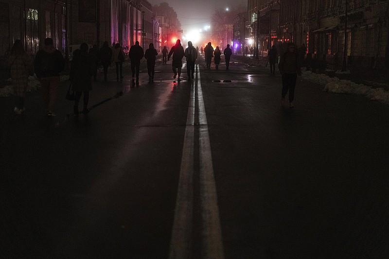 FILE - People walk through the city center which lost electrical power after yesterday's Russian rocket attack in Kyiv, Ukraine, Nov. 24, 2022. The hard realities of Ukraine’s capital are that a once comfortably livable city of 3 million people is now becoming a tough place to live. But Kyiv has hope, resilience and defiance in abundance. And perhaps more so now than at any time since Russia invaded Ukraine nine months ago. (AP Photo/Evgeniy Maloletka, File)