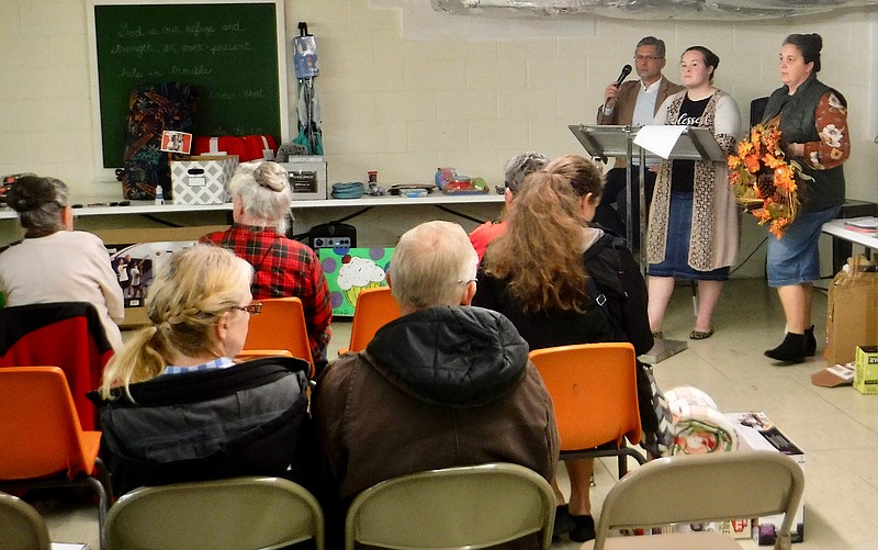 Westside Eagle Observer/SUSAN HOLLAND
Auctioneer Adam Buckler takes bids at a benefit auction, held Friday evening, Nov. 18, at the Gravette Holiness Bible School. He is assisted by Lanae Whitaker, who records purchases, and his wife, Stacey Buckler, who displays merchandise. The auction included a wide variety of donated items, all new. A bake sale, with many homemade pies, cakes, cupcakes, cookies and breads, was also held to benefit GHBS and raffle tickets were sold for two baskets filled with fall-themed merchandise. Chili and loaded nachos were served and each meal included a drink and dessert.