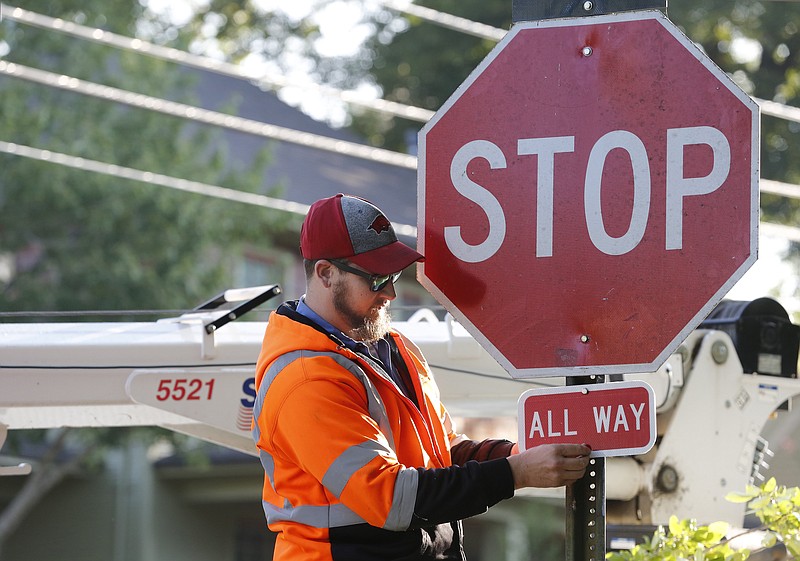 James Hoerler, with the city of Fayetteville Transportation Department, bolts in a supplemental ALL WAY plaque Monday, September 21, 2020, under a stop sign at the intersection of Spring Street and Church Avenue in Fayetteville. (NWA Democrat-Gazette/David Gottschalk)