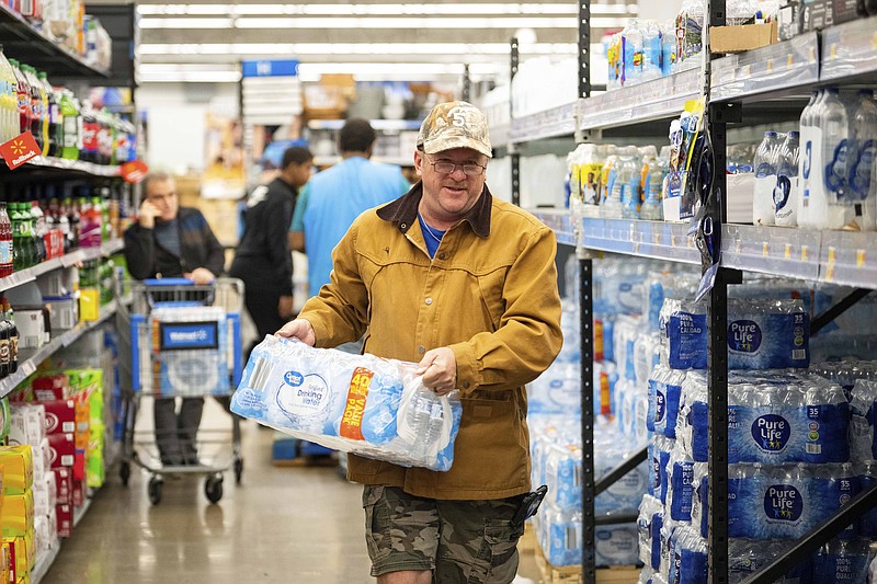 John Beezley, of Bonham, Texas, buys cases of water Sunday, Nov. 27, 2022, at a Houston Walmart after learning that a boil water notice was issued for the entire city of Houston. Beezley just arrived in town with his wife, who is undergoing treatment at M.D. Anderson Cancer Center, where they are staying in a camping trailer. They turned on the television after settling in and saw that a boil water notice had been issued. (Mark Mulligan/Houston Chronicle via AP)