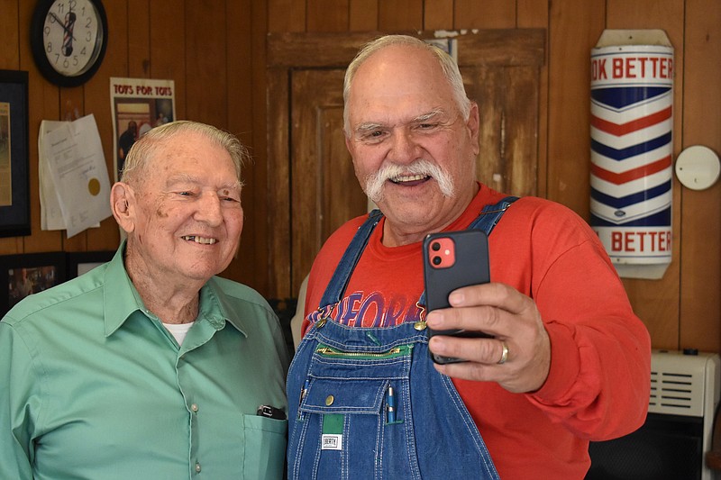 Democrat photo/Garrett Fuller — Roy Dean Simpson, left, poses for a photo with customer Norman Rohrbach on Monday at Simpson's barbershop, 511 N. High St., while celebrating the 70th anniversary of his shop. Simpson opened the shop Nov. 28, 1952, after an 18-month apprenticeship.