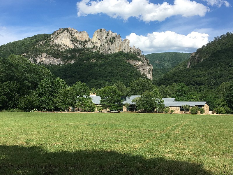 FILE - Seneca Rocks rises behind the Monongahela National Forest Discovery Center in eastern West Virginia, June 24, 2017. A program offering cash and free outdoor adventures to remote workers to move to West Virginia with the hope of offsetting population losses has welcomed 143 new residents in the year since it launched, officials announced Tuesday, Nov. 29, 2022. (AP Photo/Michael Virtanen, File)