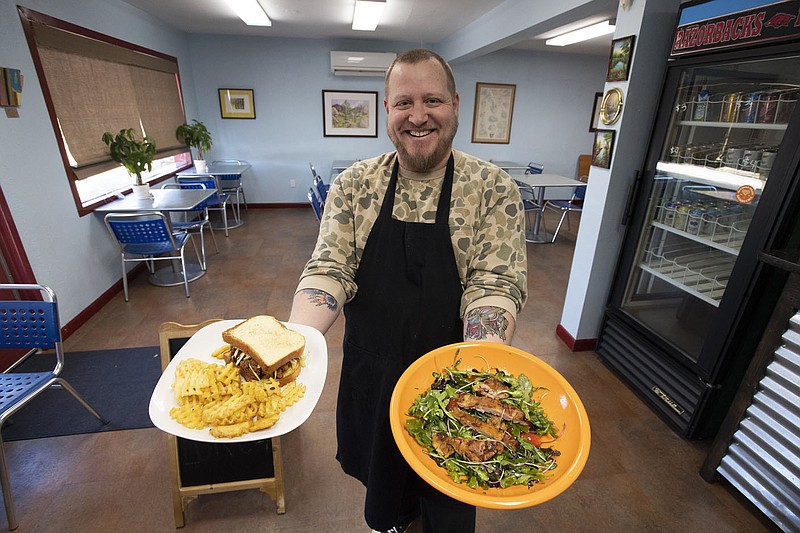 Owner and chef Ahren Boulanger holds an organic spring mix salad with grilled chicken and a fried chicken sandwich at the Pleasant Counter in Springdale Wednesday Nov. 30, 2022. The restaurant recently opened at 907 S. Pleasant St. The small restaurant aims to serve locally sourced comfort food made with quality ingredients. A grand opening will be held on Dec. 17. The current hours are Wednesday through Saturday 11 a.m. to 3 p.m.  Visit nwaonline.com/photo for today's photo gallery.   (NWA Democrat-Gazette/J.T. Wampler)