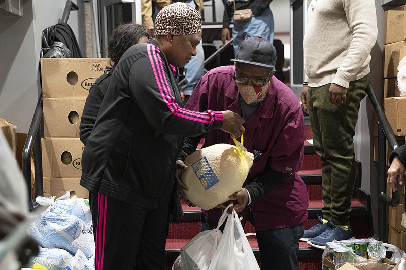 Ricardo Barrett, of Washington, accepts a turkey from church volunteer Rita James, left, during an annual Thanksgiving food giveaway at The Redeemed Christian Church of God New Wine Assembly, Tuesday, Nov. 22, 2022, in Washington. &quot;Prices went up and a lot of jobs were lost this year,&quot; says Barrett, &quot;times are hard.&quot; (AP Photo/Jacquelyn Martin)