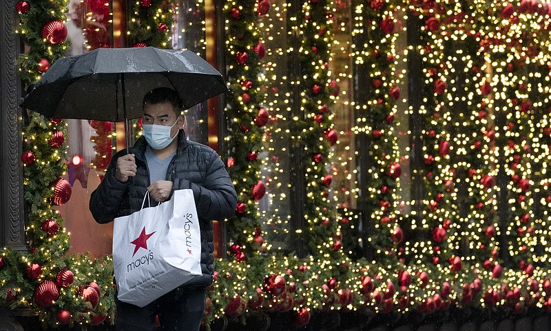 FILE - In this Nov. 30, 2020 file photo, a shopper walks by a holiday window display in New York. Financial educators are often working on overdrive during the holiday shopping season, dispensing advice to consumers about budgeting and staying out of debt. We asked five financial educators how they personally survive the holiday season with their finances intact. They shared some novel strategies, such as saving for the season starting in January and even buying gifts that early, giving nontraditional presents and focusing on next year’s financial goals instead of gifts. (AP Photo/Mark Lennihan, File)