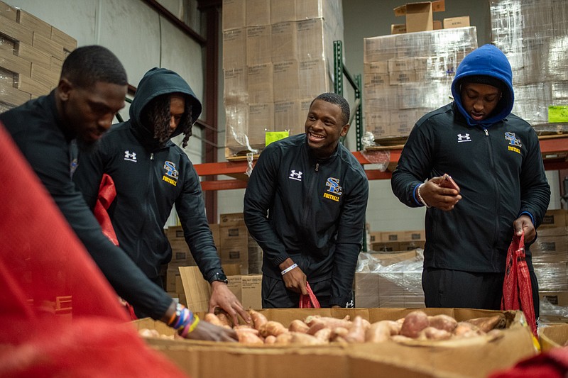 Latrell Blakey, Keelen Chilton, Marquis Gray and Alex Reeder of Southeastern Oklahoma State University football team participate in sweet potato packing on Thursday evening at Harvest Texarkana Regional Food Bank.  Approximately 170 players from Southeastern Oklahoma State and Emporia State raced one another to pack over 40,000 sweet potatoes and will be competing with one another again this weekend in this year's Live United Bowl game. The Live United Bowl has raised over $48,000 for United Way of Greater Texarkana since the inaugural game in 2013.  The game is scheduled for a noon kickoff Saturday, Dec. 3, 2022, at Arkansas High School's Razorback Stadium.  (Staff photo by Erin DeBlanc)