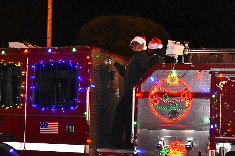 Engineers with the Pine Bluff fire department wave to the crowd during the city's Christmas parade Thursday heading north on Main Street. (Pine Bluff Commercial/I.C. Murrell)