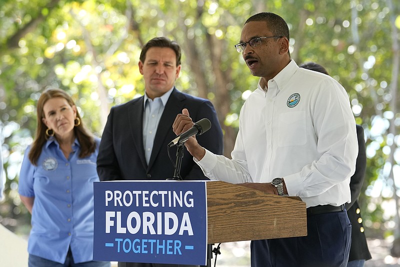 Shawn Hamilton, secretary of the Florida Department of Environmental Protection, right, speaks during a news conference at Bill Baggs Cape Florida State Park, Thursday, Dec. 1, 2022, on Key Biscayne, Fla. Florida Gov. Ron DeSantis, center, announced increased funding for the environmental protection of Biscayne Bay. (AP Photo/Lynne Sladky)