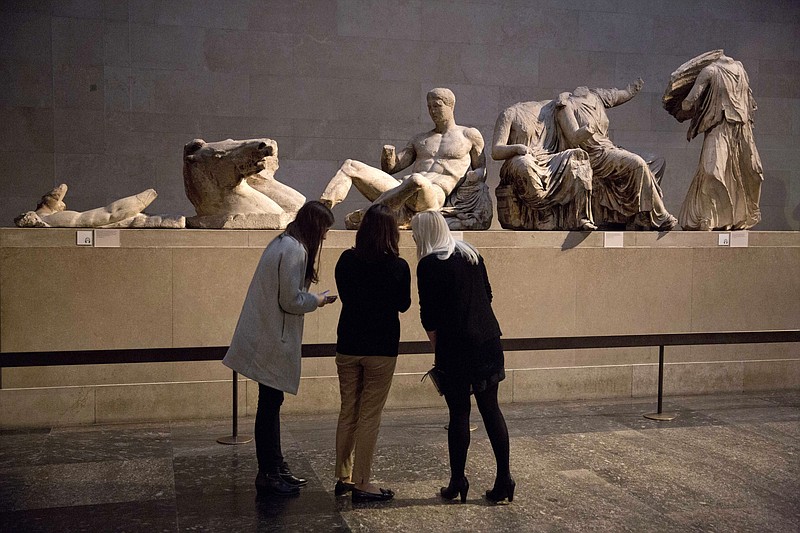 Women stand by a marble statue of a naked youth thought to represent Greek god Dionysos, center, from the east pediment of the Parthenon, on display during a media photo opportunity to promote a forthcoming exhibition on the human body in ancient Greek art at the British Museum in London, Thursday, Jan. 8, 2015. The British Museum has pledged not to dismantle its collection following a report that the institution’s chairman has held secret talks with Greece’s prime minister over the return of the Parthenon Sculptures, also known as the Elgin Marbles. (AP Photo/Matt Dunham, File)