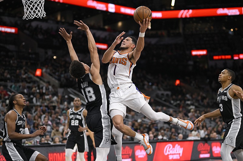 Phoenix Suns' Devin Booker (1) shoots against San Antonio Spurs' Isaiah Roby during the first half of an NBA basketball game, Sunday, Dec. 4, 2022, in San Antonio. (AP Photo/Darren Abate)