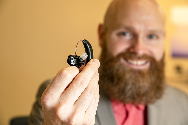 Sterling Sheffield, an assistant professor of Speech, Language, and Hearing Sciences at the University of Florida, holds an over-the-counter hearing aid Wednesday, Nov. 30, 2022, in Gainesville, Fla. OTC hearing aids started hitting the market in October after the FDA approved them for adults with mild-to-moderate hearing loss, and Sheffield has been testing them. (AP Photo/Alan Youngblood)