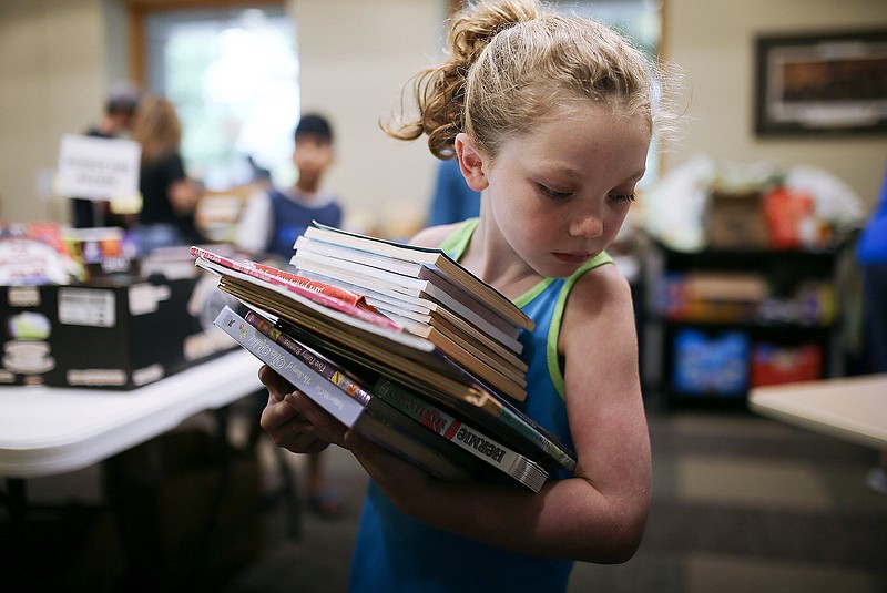 Reagan Caspermeyer, 7, of Bentonville carries a big stack of books July 29 at the Bentonville Public Library in Bentonville. Visit nwaonline.com for today's photo gallery.

(File Photo/NWA Democrat-Gazette/Charlie Kaijo)