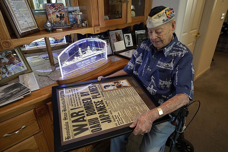 CORRECTS AGE TO 101 INSTEAD OF 102 - Pearl Harbor survivor Lou Conter, 101, holds a framed replica of the Honolulu Star-Bulletin of Dec. 7, 1941 at his home in Grass Valley, Calif., Friday, Nov. 18, 2022. Conter survived the devastating explosion that destroyed the battleship, USS Arizona, during the Japanese attack on Pearl Harbor, Dec. 7, 1941.(AP Photo/Rich Pedroncelli)