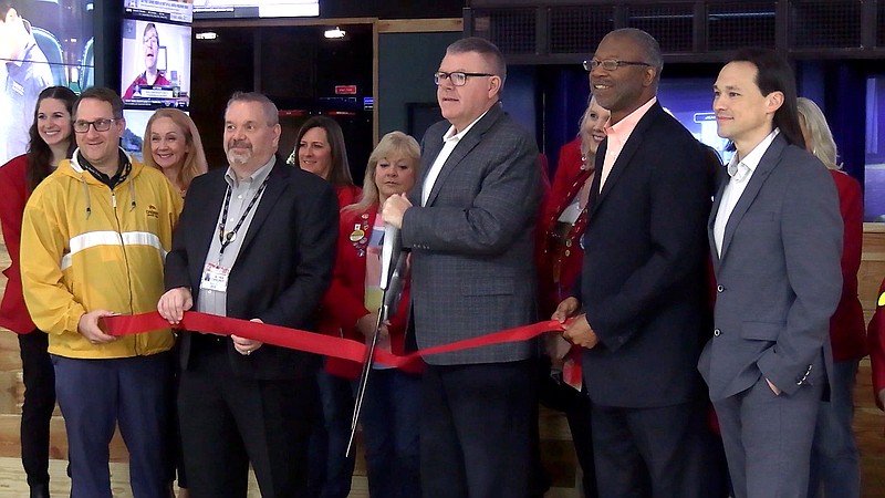 Oaklawn Racing Casino Resort General Manager Wayne Smith, center, cuts the ribbon while surrounded by Oaklawn staff members and members of The Greater Hot Springs Chamber of Commerce Red Coats Thursday in front of Oaklawn's new Mainline Sports Bar and Sportsbook. - Photo by Lance Porter of The Sentinel-Record