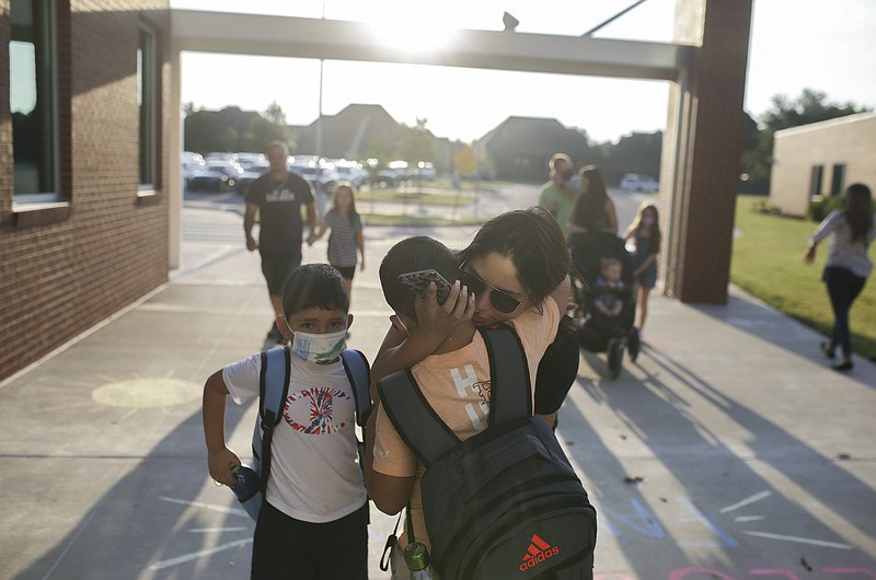 Leslie Matar (center right) hugs Zariel Enriquez, 8, (center) before dropping off him and his brother Jassiel Enriquez, 7, on their first day of school Aug. 16, 2021, at Fairview Elementary School in Rogers. 
(File Photo/NWA Democrat-Gazette/Charlie Kaijo)