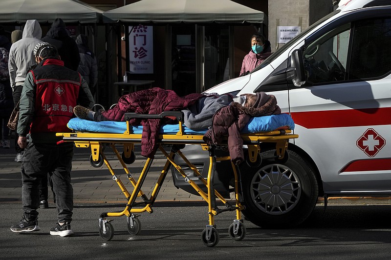 An elderly woman on a stretcher is wheeled into the fever clinic at a hospital in Beijing, Sunday, Dec. 11, 2022. Facing a surge in COVID-19 cases, China is setting up more intensive care facilities and trying to strengthen hospitals as Beijing rolls back anti-virus controls that confined millions of people to their homes, crushed economic growth and set off protests. (AP Photo/Andy Wong)