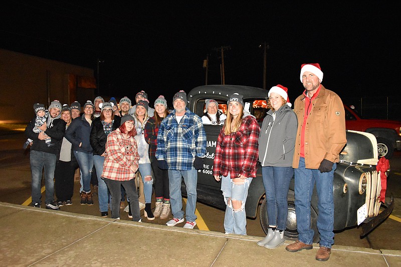 Democrat photo/Garrett Fuller — The family of Tommy and Suzy Green pose for a photo Saturday prior to the Jamestown Christmas parade with the 1945 Ford pickup truck Jon Imhoff restored since his uncle Tommy died in November 2018. The former mail truck was built in 1945 during World War II, when civilian vehicle production was limited by the war effort. Suzy Green is pictured inside the truck, and Imhoff is at the right end of the group.