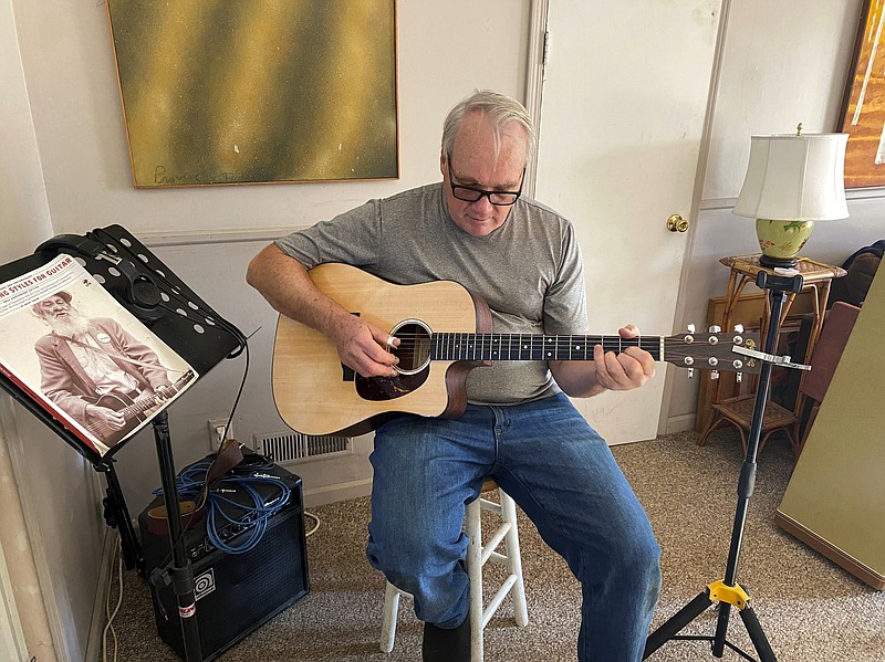 Bob Dorobis plays his guitar at home in Middletown, N.J., on Dec. 4. Dorobis redoubled his efforts to learn fingerpicking during the pandemic. (Jeanann Dorobis via AP)