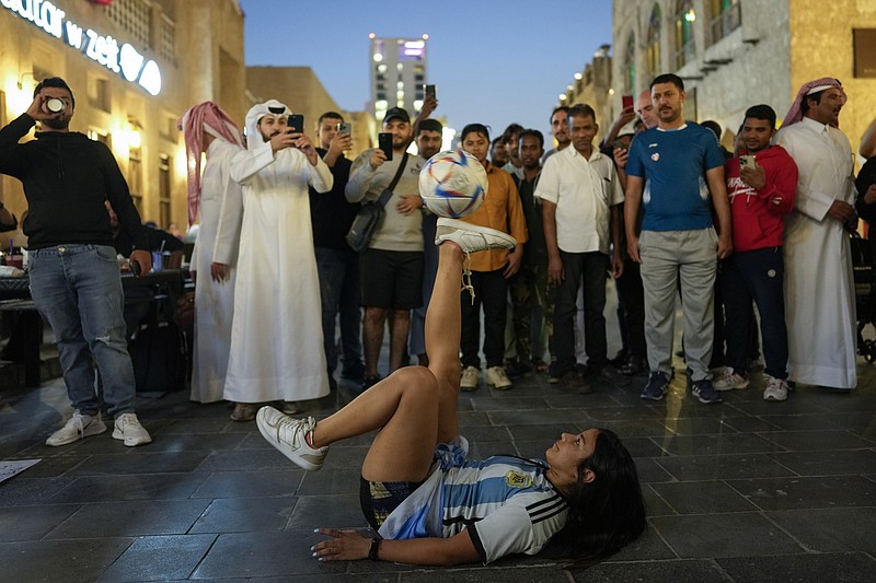 Belén Godoy, de Argentina, hace malabares con una pelota para conseguir el dinero que le permita comprar una entrada de la final del Mundial, en el mercado Souq Waqif de Doha, Qatar, martes 25 diciembre 2022. (AP Foto/Andre Penner)