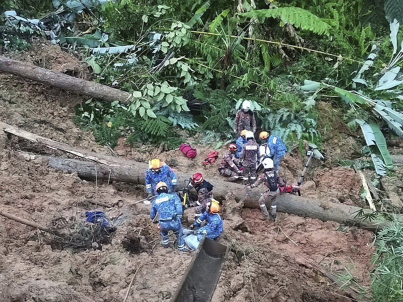 En esta foto suministrada por el Departamento de Defensa Civil, socorristas buscan personas desaparecidas tras un deslave en un campamento de Batang Kali, Malasia, el viernes 16 de diciembre de 2022. (Defensa Civil de Malasia vía AP )