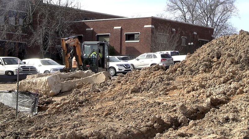 A worker with McHenry Excavators works in the empty lot between the RIX Professional Building and the Garland County Library on the library's new green space, which will include a community garden and outdoor programming space. - Photo by Lance Porter of The Sentinel-Record