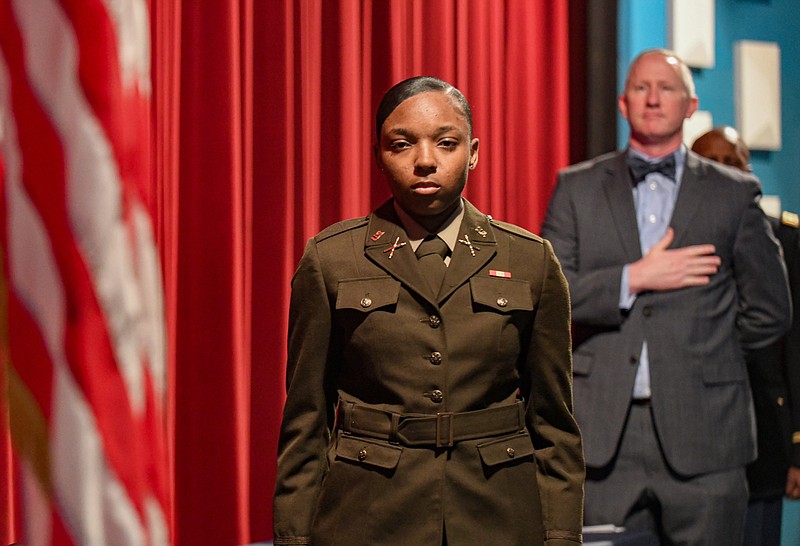 Julie Smith/News Tribune photo: 
Blue Tiger Battalion Cadet Christuanna Kelley looks toward the American flag Friday during the National Anthem at the opening of Kelley's commissioning ceremony in Pawley Theater in Martin Luther King Hall. Standing behind Kelley is Lincoln University President John Moseley. Kelley was promoted to 2nd lieutenant Friday, Dec. 16, 2022, during the ceremony. Upon graduation with a B.S. in Business Administration, Kelley will report to a field artillery division at Fort Sill, OK, as the first female to graduate from LU ROTC in combat arms.