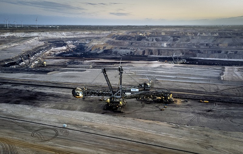 FILE - A bucket wheel excavator is mining coal at the Garzweiler open-cast coal mine with wind turbines in the background in Luetzerath, Germany, on Nov. 2, 2022. Coal use across the world is set to reach a new record this year amid persistently high demand for the heavily polluting fossil fuel, the International Energy Agency said Friday, Dec. 16, 2022. The Paris-based agency said in a new report that while coal use grew by only 1.2% in 2022, the increase pushed it to all all-time high of more than 8 billion metric tons, beating the previous record set in 2013. (AP Photo/Michael Probst)