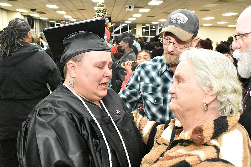 Jessica Derrick, filled with emotion, hugs her soon-to-be mother-in-law Deborah Nanny as her fiance Floyd Roberts looks on in the lobby of the Pine Bluff Convention Center following graduation from SEARK College on Friday. (Pine Bluff Commercial/I.C. Murrell)