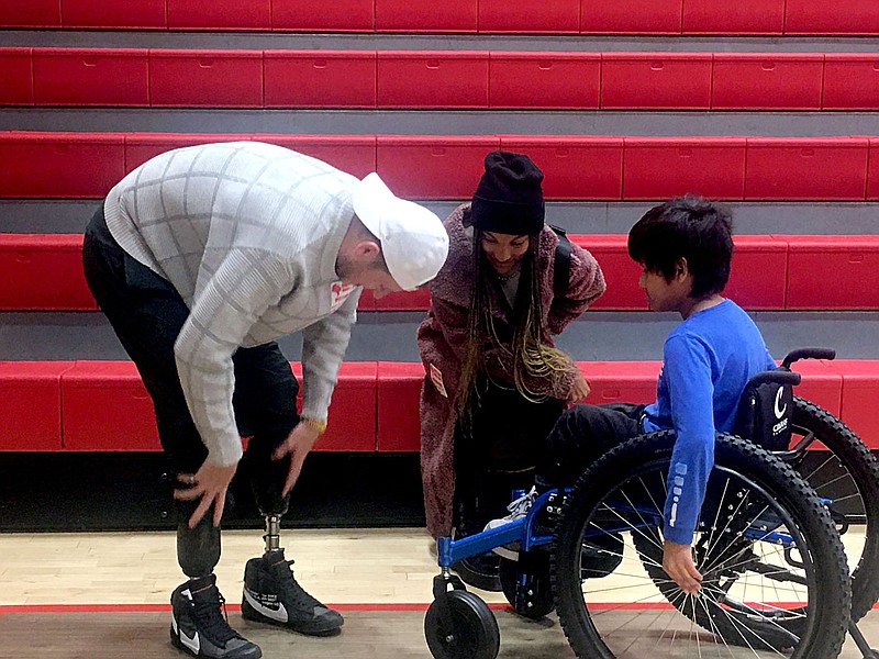 Eleven year old Angel Figueroa, a 6th grader at Greer Lingle Middle School talkes with Hunter Woodhall, a Paralympian, and his wife, Tara Davis Woodhall, Tuesday after a school assembly. Angel  is wheelchair bound, and a member of the Sixth Grade Running Club received a new custom wheelchair to aid him in the activity. (Photo by Tracy M. Neal)