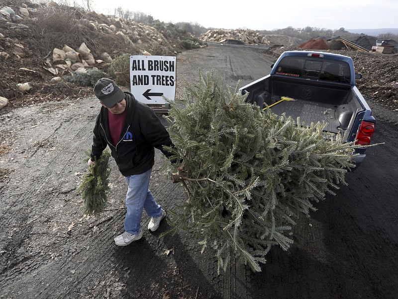 FILE- George Highhouse, of Scranton, brings his Christmas tree and a wreath to Lackawanna County Recycling in Dunmore, Pa., on Jan. 2, 2019. Discarded Christmas trees can be picked up curbside for recycling through regular trash-collection services or or dropped off at locations in various cities. The trees are often shredded for use as compost or mulch that is offered back to residents and non-profit groups free of charge for gardening and landscaping. (Jake Danna Stevens/The Times-Tribune via AP, File)