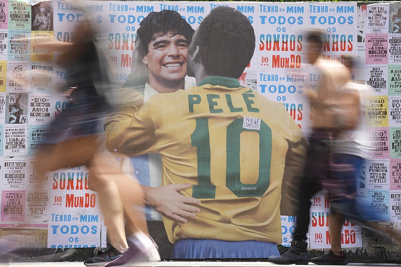 La gente pasa frente a un cartel que muestra al brasileño Pelé y al argentino Diego Maradona en Sao Paulo, el sábado 24 de diciembre de 2022 (AP Foto/Andre Penner)