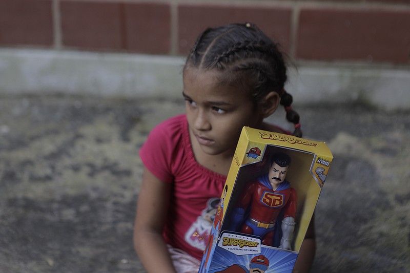 Una niña con su muñeco de Super Bigote en el vecindario Carayaca de La Guaira, Venezuela, el martes 27 de diciembre de 2022. La entrega de juguetes de Super Bigote o de Cilita, inspirados en la imagen del presidente de Venezuela Nicolás Maduro y de su esposa Cilia Flores se dirigió a miles de niños por Navidad, lo que levantó polémica entre algunos venezolanos. (AP Foto/Jesus Vargas)