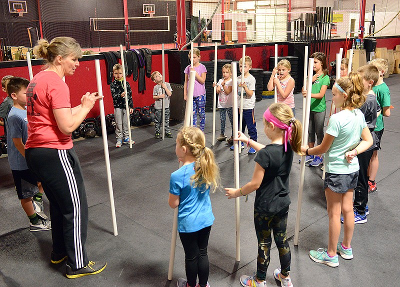 Sally Ince/ News Tribune
Fitness coach Debbie Rosslan shows children how to practice their coordination skills Thursday January 2, 2020 as they participate in a game to balance pvc pipes during a Christmas Break Kids Camp at CrossFit Unstoppable. Participants in the camp were tought new games, workout routines and were able to use areas of the gym for playtime. The gym will also be offering two kids fitness classes for ages 4-7 and 8-12 every Tuesday and Thursday beginning January 14.