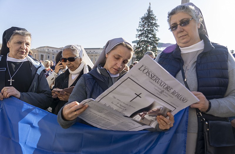 Nuns read the Vatican newspaper L'Osservatore Romano bearing the news of the death of Pope Emeritus Benedict XVI as they wait for Pope Francis to appear at his window overlooking St. Peter's Square at The Vatican for the traditional noon blessing Sunday, Jan. 1, 2023. Pope Benedict, the German theologian who will be remembered as the first pope in 600 years to resign, has died, the Vatican announced Saturday Dec. 31, 2022. He was 95. (AP Photo/Domenico Stinellis)