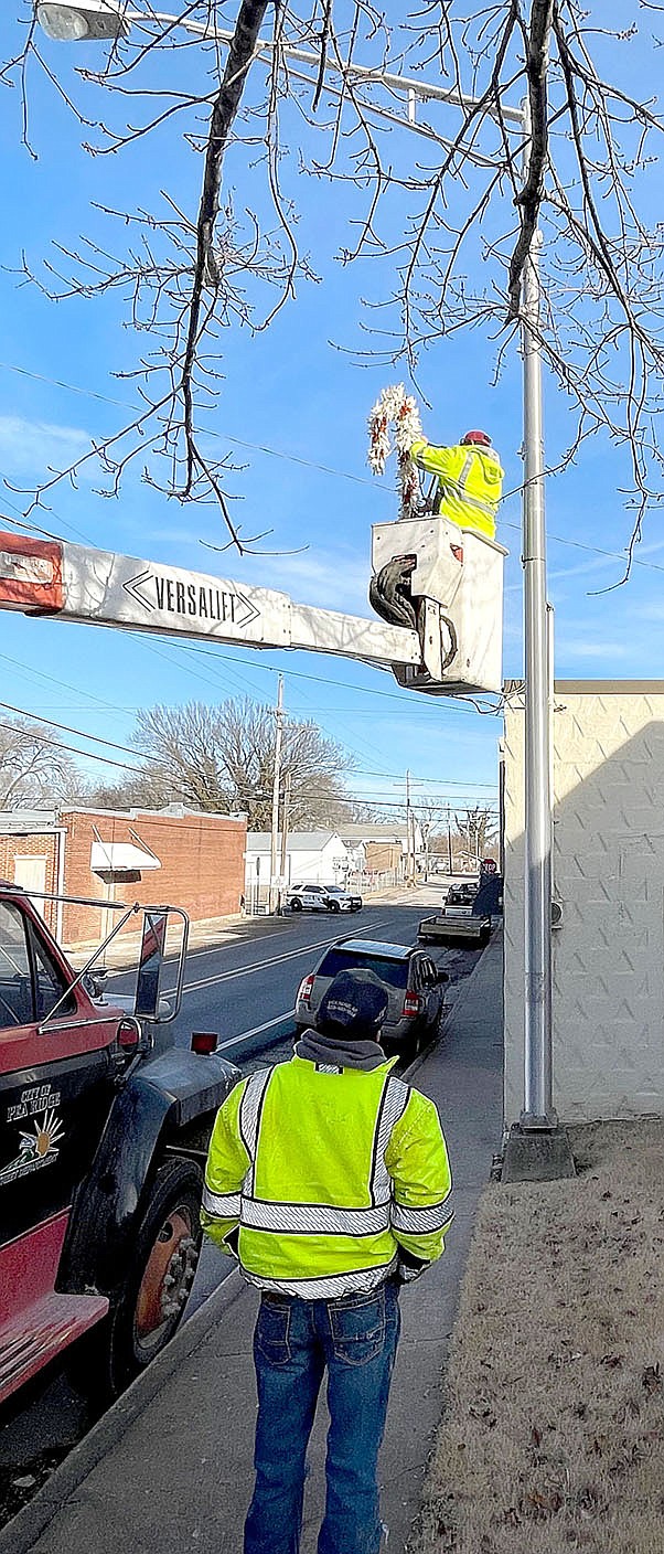 TIMES photograph by Annette Beard
Street Department employees Hagen Schader (in the bucket) and Sawyer Varner took down Christmas decorations off the street light poles and placed American flags on the poles Friday, Dec. 23, 2022.