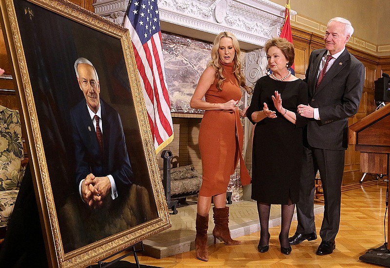 Gov. Asa Hutchinson (right) first lady Susan Hutchinson (center) and their daughter, Sarah, look at the governor's new portrait which was unveiled on Tuesday, Jan. 3., 2023, at the state Capitol in Little Rock. 
(Arkansas Democrat-Gazette/Thomas Metthe)