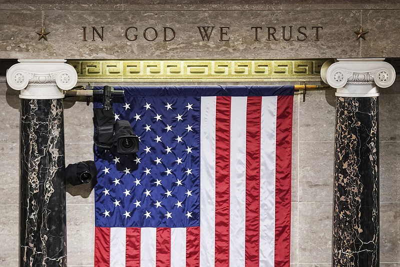 "In God We Trust" engraved in stone above a U.S. flag in the House of Representatives chamber is seen March 1, 2022, at the Capitol in Washington. Even though nearly three in 10 Americans claim no religious affiliation — a rate that has steadily risen in recent years — only two of the 534 incoming members of Congress will admit to as much. (Sarahbeth Maney/The New York Times via AP, Pool)