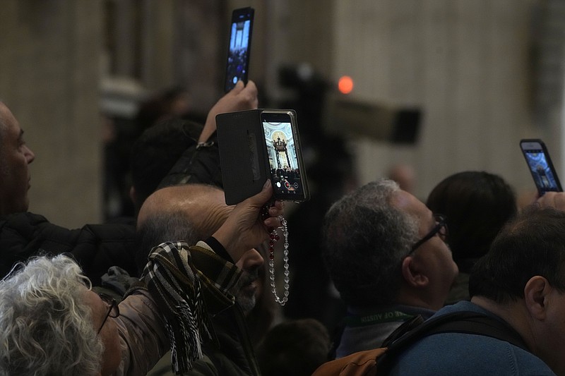 People film the body of late Pope Emeritus Benedict XVI lied out in state inside St. Peter's Basilica on Wednesday, Jan. 4, 2023, at the Vatican. Benedict, the German theologian who will be remembered as the first pope in 600 years to resign, died Saturday, Dec. 31, 2022. He was 95.(AP Photo/Gregorio Borgia)